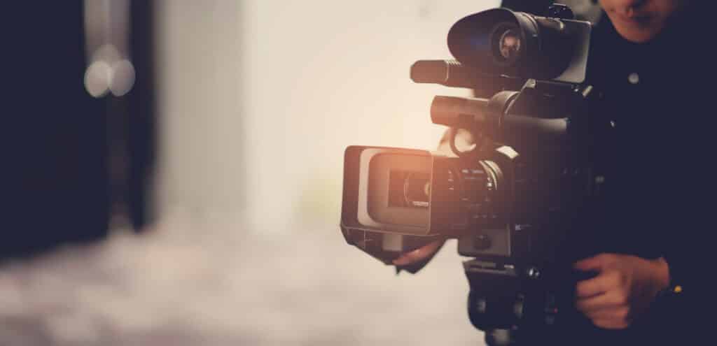 Personne filmant avec une caméra vidéo professionnelle lors d'un événement. Gros plan sur la caméra.